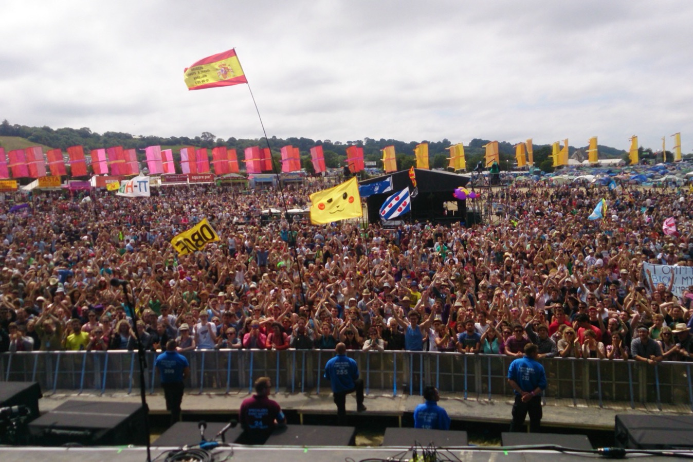A huge festival crowd with flags, seen from the stage.