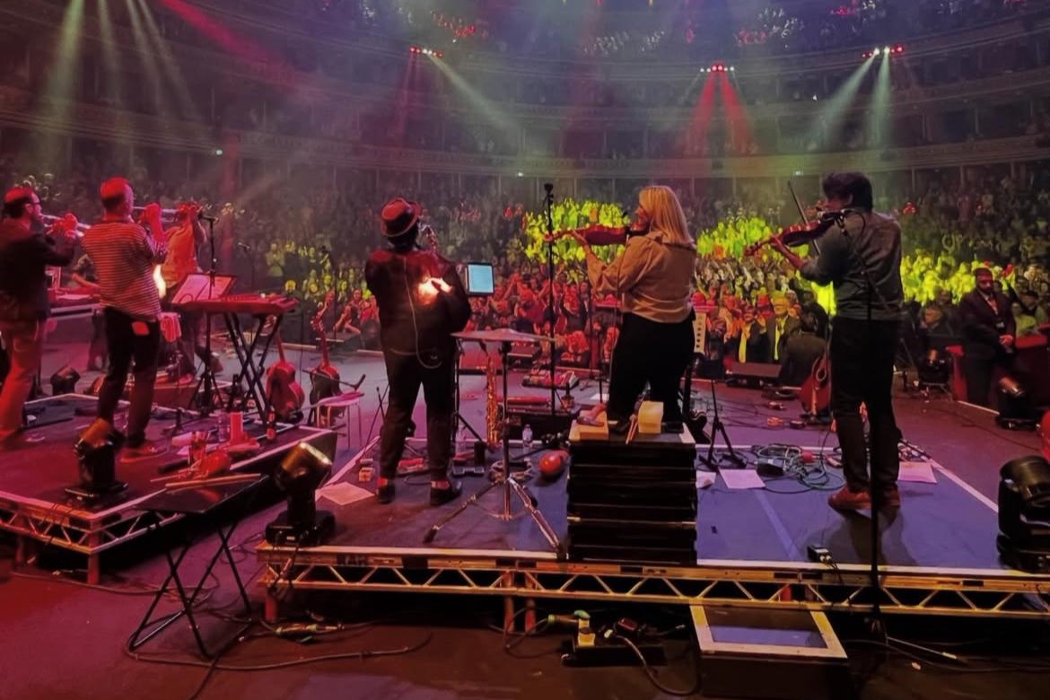 Stornoway on stage at the Royal Albert Hall, seen from behind the band, with the audience lit up beyond.